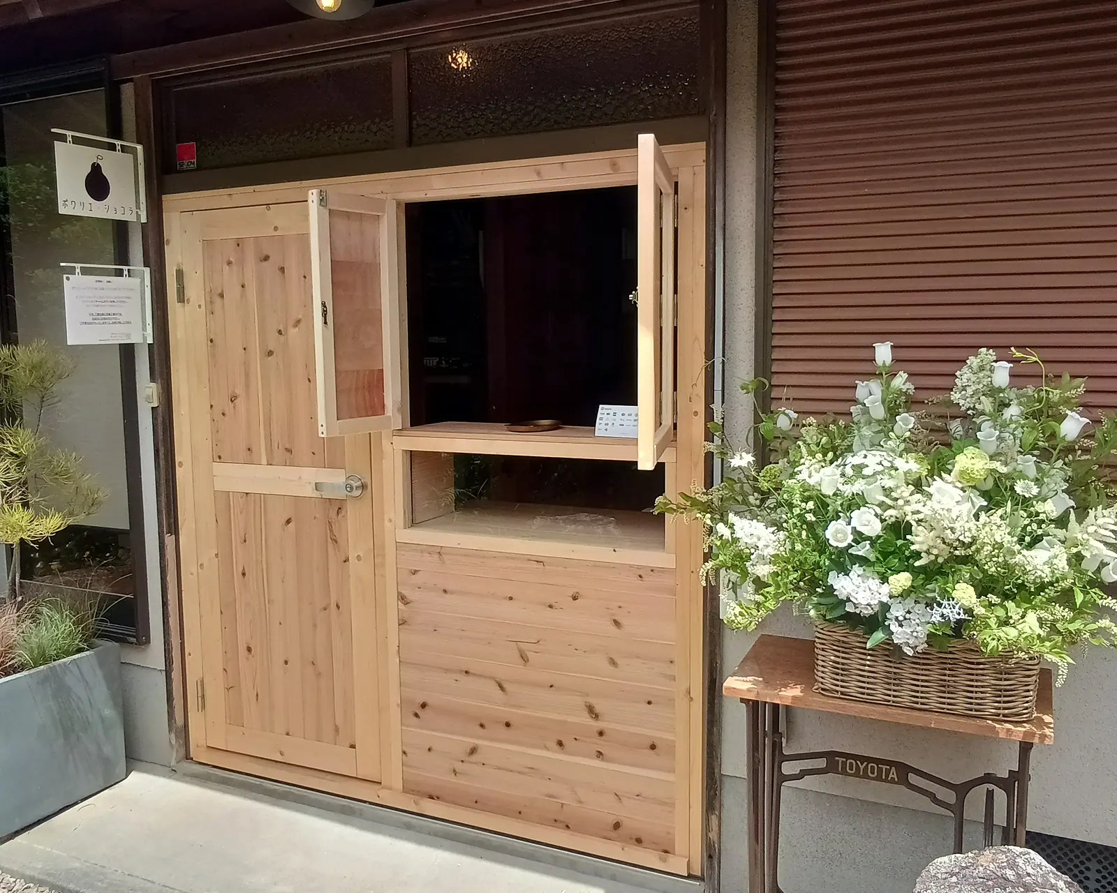 白い花を飾ったポワリエ・ショコラ工房の受け取り窓
